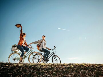 Paar fährt Fahrrad am sonnigen Herbsttag | © GettyImages/StefaNikolic