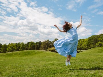 Frau hüpft auf einer grünen Wiese und ist glücklich | © GettyImages/Svetlana Iakusheva