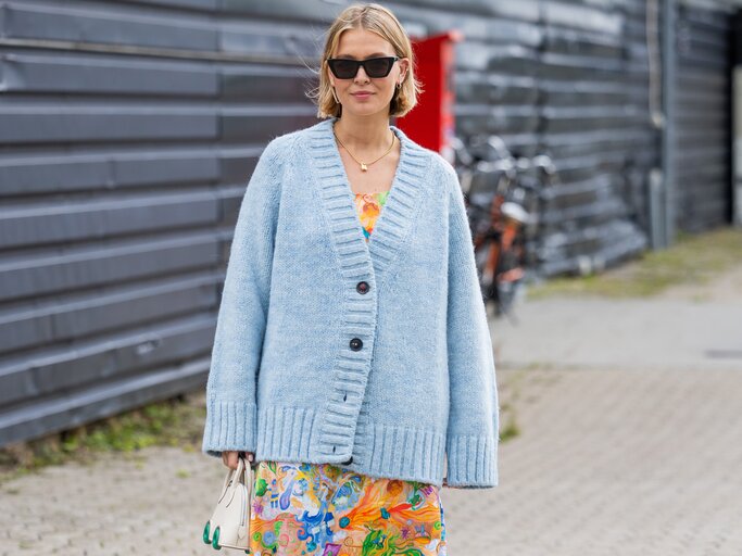 Frau trägt Blumenkleid mit Cardigan | © GettyImages/Christian Vierig