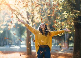 Frau wirbelt Herbstlaub auf