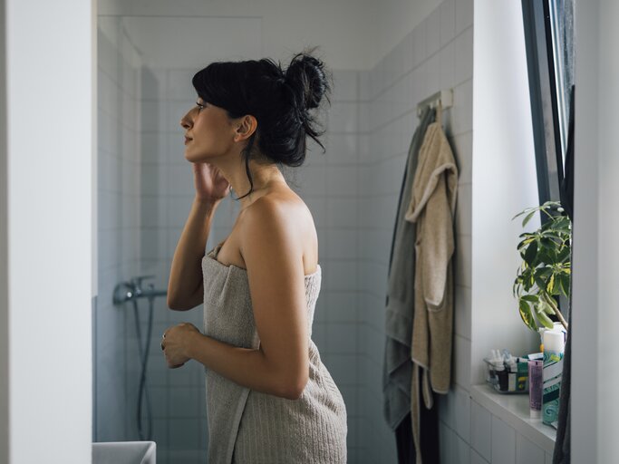 Frau steht im Bad nach einer Dusche | © GettyImages/FreshSplash