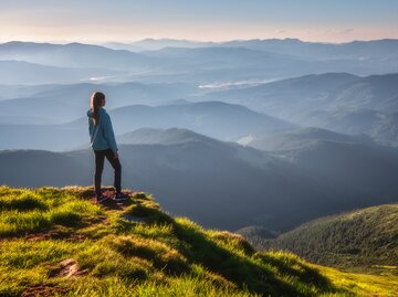 Frau steht oben am Berg | © AdobeStock/den-belitsky