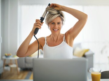 Frau macht sich mit einem Lockenstab Locken | © GettyImages/	Aja Koska