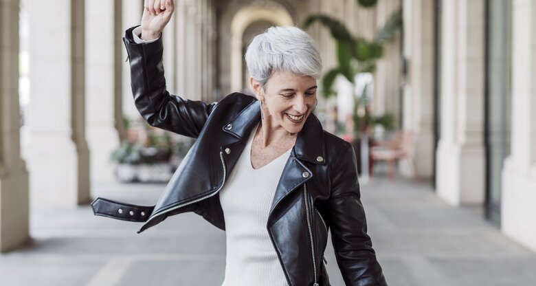 Frau mit grauen Haaren tanzt glücklich  | © GettyImages/	COROIMAGE