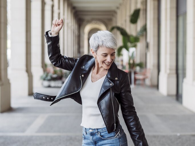 Frau mit grauen Haaren tanzt glücklich  | © GettyImages/	COROIMAGE