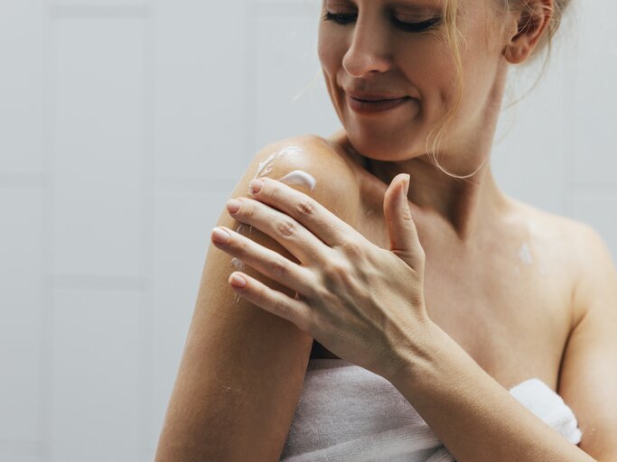 Frau cremtich mit Bodylotion ein | © GettyImages/FreshSplash