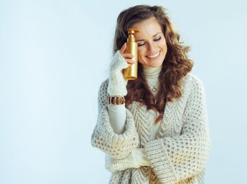 Winterlich angezogene Frau mit Selbstbräuner | © GettyImages/	CentralITAlliance