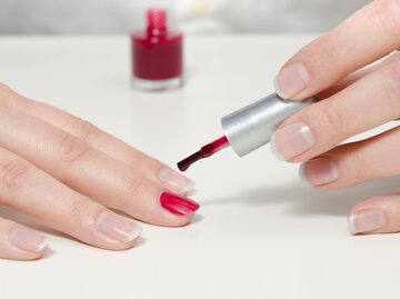 Frau lackiert sich Nägel mit rotem Nagellack | © AdobeStock/frankdaniels