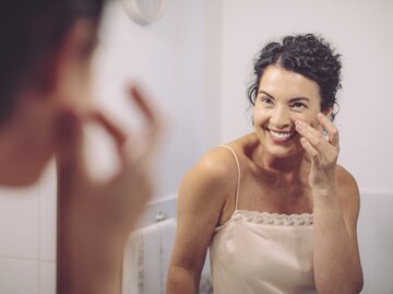 Reife Frau blickt in den Spiegel | © GettyImages/	Eva-Katalin