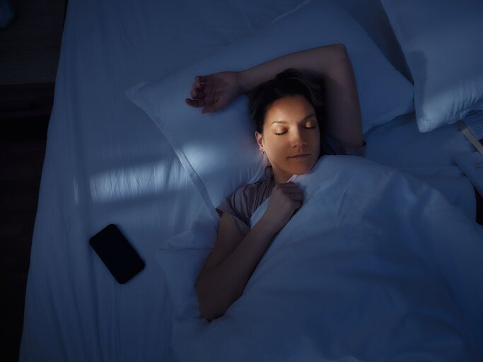 Frau schläft neben ihrem Handy | © GettyImages/skynesher