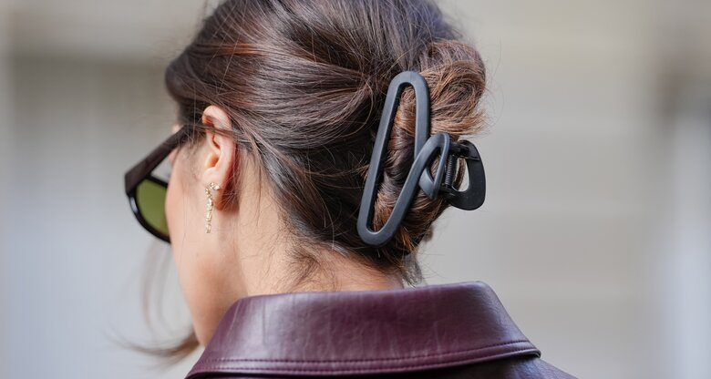 Frau mit braunen Haaren trägt schwarze Haarklammer | © GettyImages/	Edward Berthelot