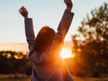 Junge Frau freut sich über den Sonnenuntergang in der Natur | © Getty Images/Oscar Wong