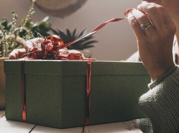 Die Hand einer Frau packt ein Geschenkebox aus. | © Adobe Stock/simona