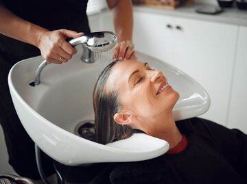 Person lässt sich bei Friseur Haare waschen | © Getty Images/PeopleImages