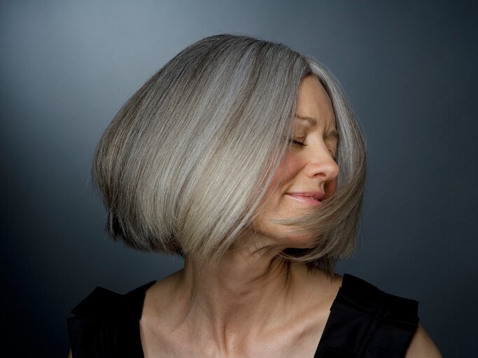 Eine Frau dreht den Kopf zur Seite und präsentiert ihre schönen grauen Haare | © GettyImages/Ralf Nau