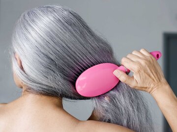 Frau kämmt ihre langen grauen Haare mit einer pinken Haarbürste. | © Getty Images / Patrik Giardino