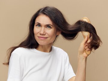 Frau kämmt ihr braunes Haar | © AdobeStock/Tatiana