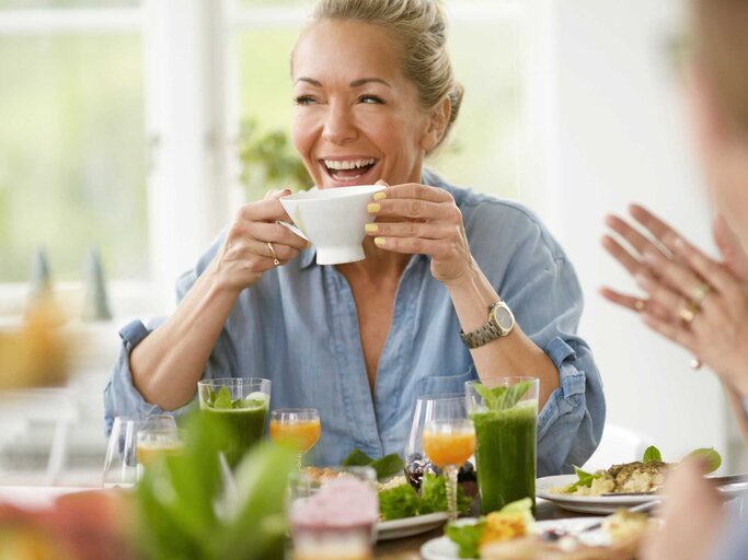 Frau frühstückt und lacht  | © Getty Images/Johner Images