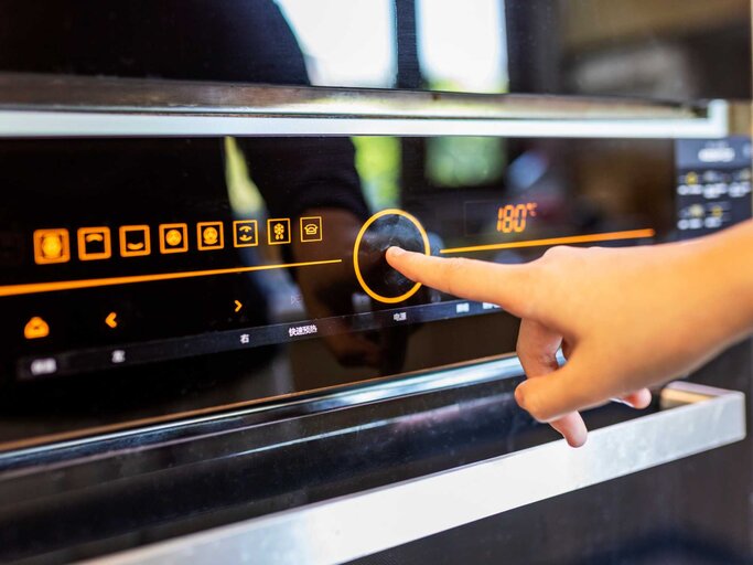 Person bedient Backofen per Touchscreen | © Getty Images/owngarden
