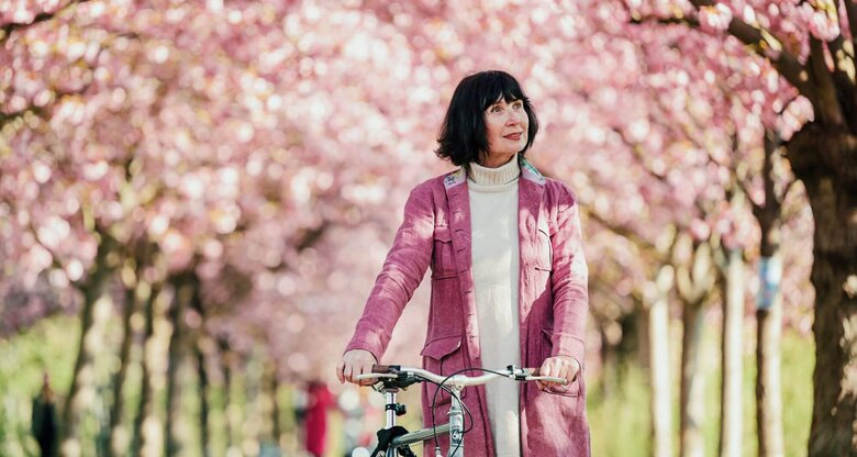 Person auf Fahrrad unter Kirschblüten | © Getty Images/Alina Rudya/Bell Collective