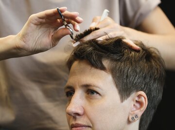 Nahaufnahme von Händen einer Friseurin, die einer Frau einen Pixie Cut schneidet | © GettyImages/Elena Popova