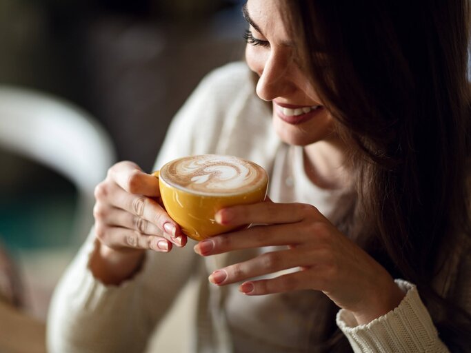 Frau lächelt, während sie ihren Kaffee genießt | © gettyimages.de /  Drazen Zigic