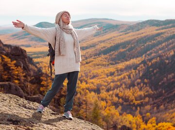 Frau steht am Berg und atmet tief durch | © Adobe/StockTatyana Gladskih